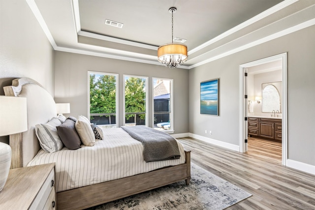 bedroom featuring visible vents, baseboards, ornamental molding, a tray ceiling, and light wood-type flooring