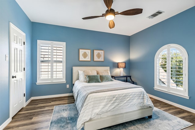 bedroom featuring a ceiling fan, wood finished floors, visible vents, and baseboards