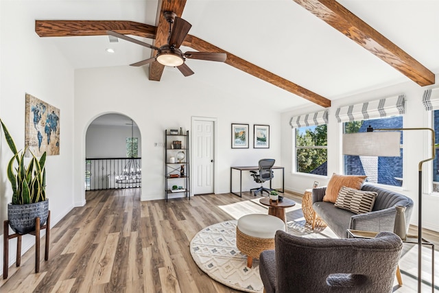 living area featuring arched walkways, vaulted ceiling with beams, baseboards, and wood finished floors