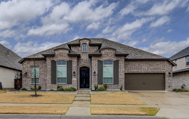 french provincial home with a garage, brick siding, concrete driveway, and a shingled roof