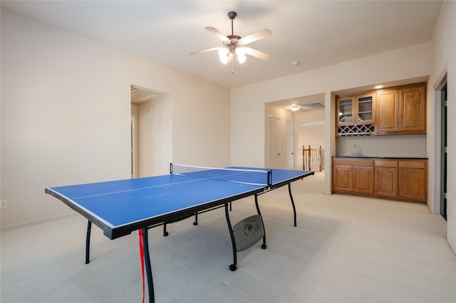 game room featuring bar, light carpet, and ceiling fan