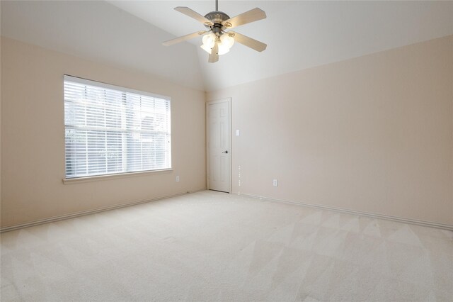 spare room with a ceiling fan, lofted ceiling, light colored carpet, and baseboards