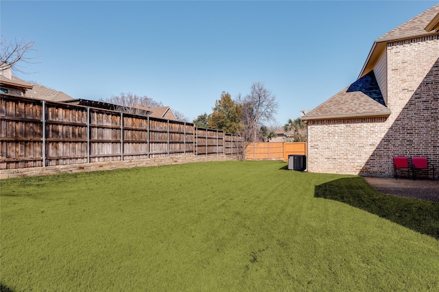 view of yard with a fenced backyard and central AC