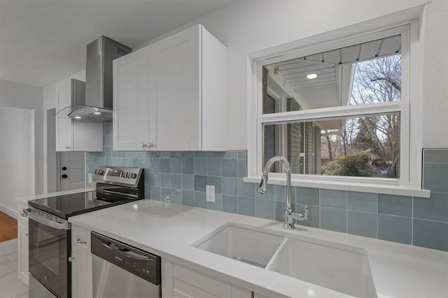 kitchen with white cabinetry, sink, stainless steel appliances, and wall chimney exhaust hood