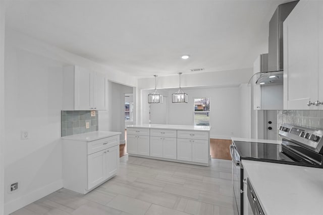 kitchen with white cabinetry, hanging light fixtures, electric range, decorative backsplash, and wall chimney exhaust hood