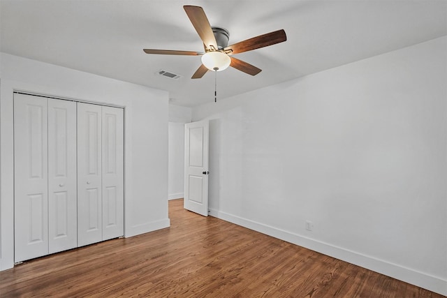 unfurnished bedroom with ceiling fan, wood-type flooring, and a closet