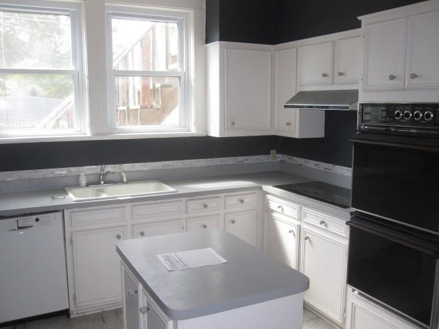 kitchen featuring extractor fan, sink, white cabinetry, a kitchen island, and black appliances