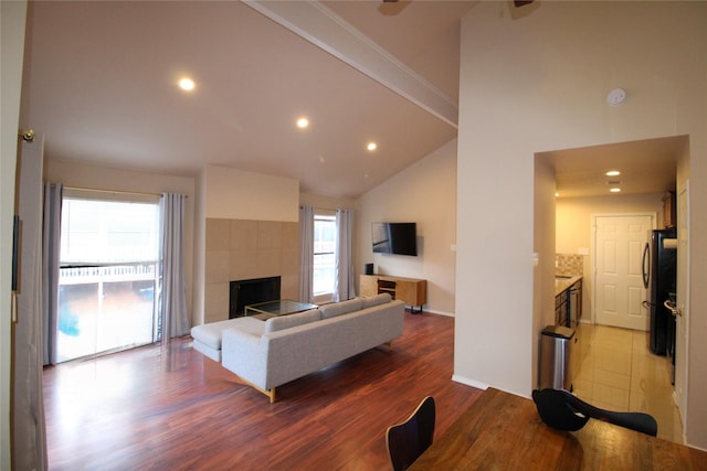 living room with high vaulted ceiling, hardwood / wood-style floors, and a fireplace