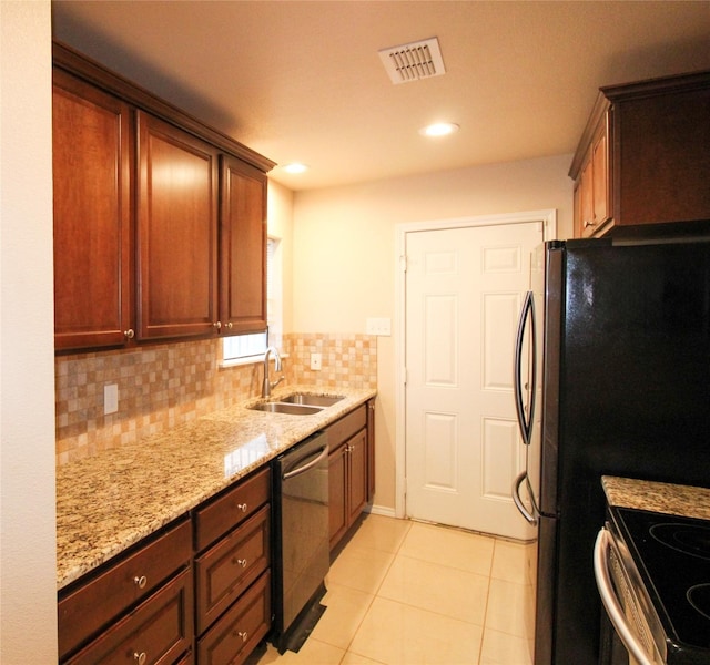 kitchen featuring light tile patterned flooring, sink, backsplash, light stone counters, and stainless steel appliances