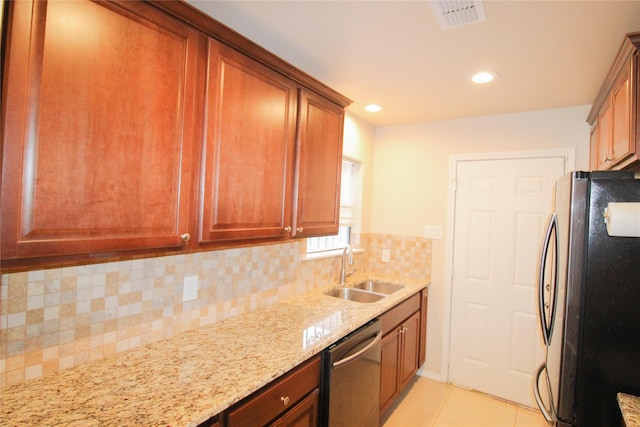 kitchen featuring appliances with stainless steel finishes, sink, decorative backsplash, light tile patterned floors, and light stone counters