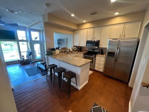 kitchen with white cabinets, a peninsula, appliances with stainless steel finishes, and dark wood finished floors