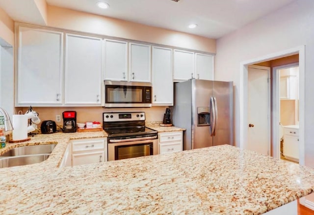 kitchen featuring a sink, appliances with stainless steel finishes, light stone countertops, and recessed lighting