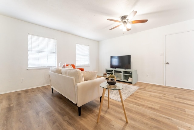 living area featuring light wood finished floors, baseboards, and a ceiling fan