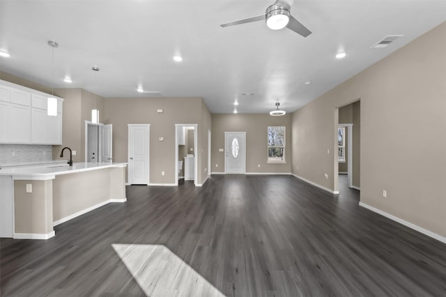 unfurnished living room featuring ceiling fan, dark hardwood / wood-style flooring, and sink