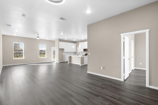 unfurnished living room featuring sink, dark wood-type flooring, and ceiling fan