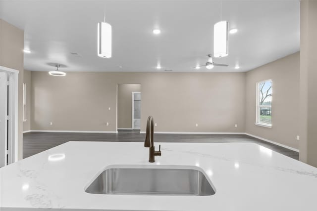 kitchen with pendant lighting, light stone countertops, and an island with sink