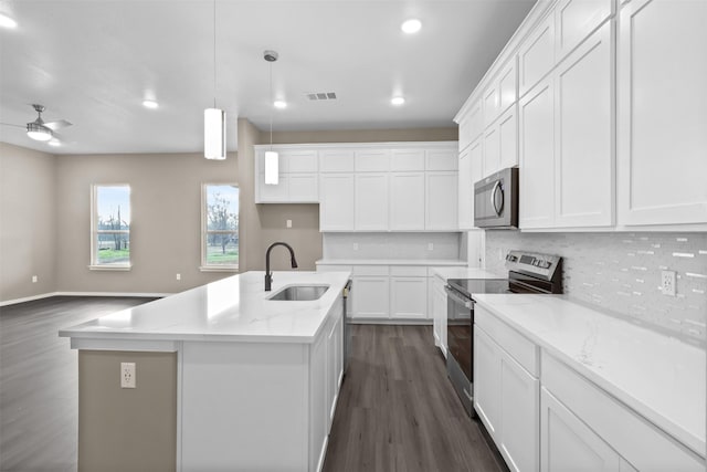 kitchen with light stone countertops, appliances with stainless steel finishes, a kitchen island with sink, and white cabinets