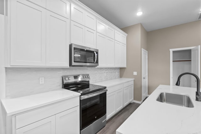 kitchen featuring sink, tasteful backsplash, stainless steel appliances, light stone countertops, and white cabinets