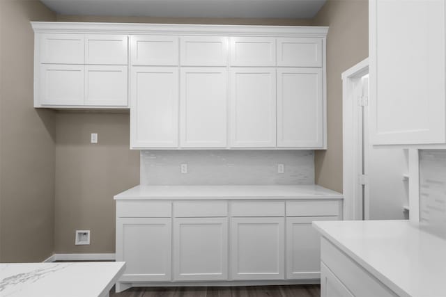 kitchen featuring backsplash, light stone counters, and white cabinets