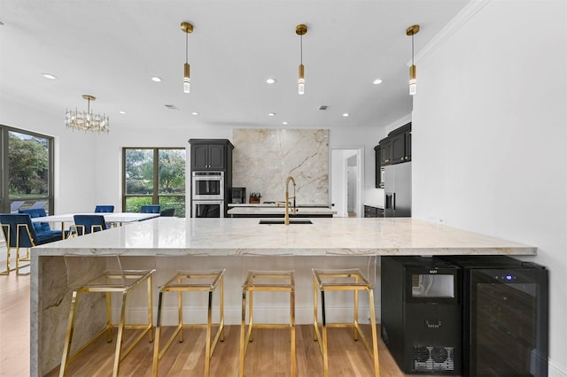 kitchen with sink, tasteful backsplash, light stone countertops, light hardwood / wood-style floors, and beverage cooler