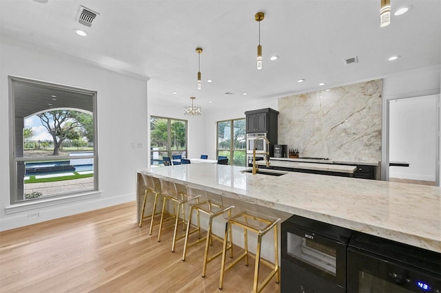 kitchen featuring pendant lighting, tasteful backsplash, a breakfast bar area, light stone counters, and light wood-type flooring