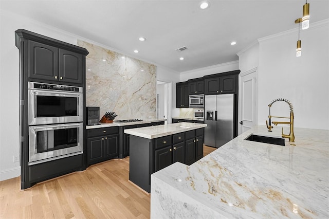 kitchen featuring sink, hanging light fixtures, stainless steel appliances, crown molding, and light stone countertops