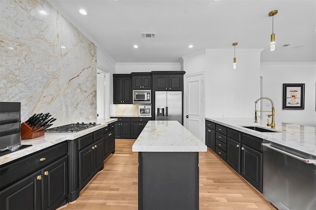 kitchen featuring a kitchen island, appliances with stainless steel finishes, pendant lighting, sink, and light wood-type flooring