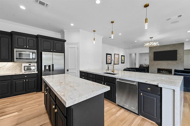 kitchen featuring sink, appliances with stainless steel finishes, a center island, light hardwood / wood-style floors, and decorative light fixtures