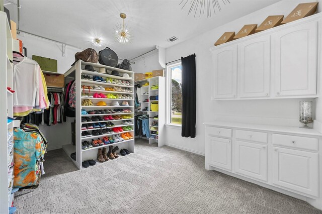 walk in closet with light colored carpet