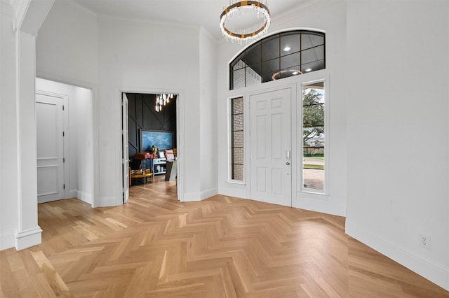 foyer with a towering ceiling, ornamental molding, and light parquet floors
