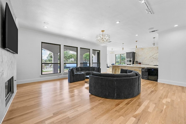 living room featuring an inviting chandelier, rail lighting, sink, and light wood-type flooring