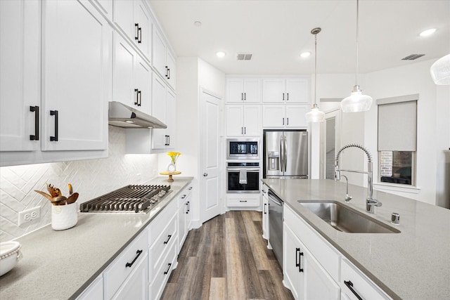 kitchen featuring appliances with stainless steel finishes, pendant lighting, white cabinetry, sink, and light stone counters