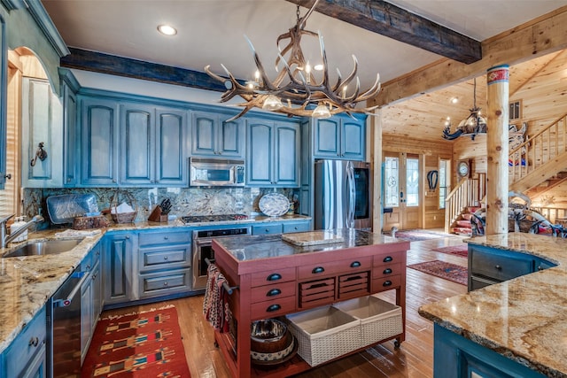 kitchen featuring sink, stainless steel appliances, light stone counters, decorative light fixtures, and a chandelier