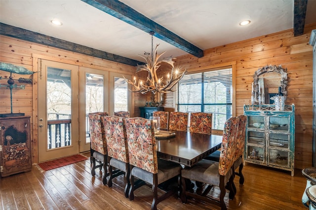 dining area with beamed ceiling, wooden walls, dark hardwood / wood-style flooring, and a chandelier