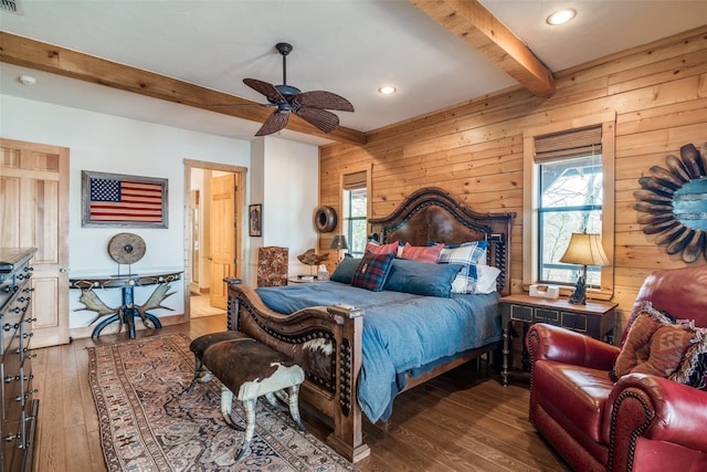 bedroom with multiple windows, beam ceiling, wooden walls, and hardwood / wood-style flooring