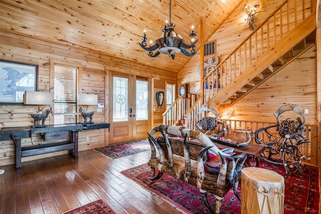 living room with lofted ceiling, wood ceiling, a chandelier, wooden walls, and hardwood / wood-style floors