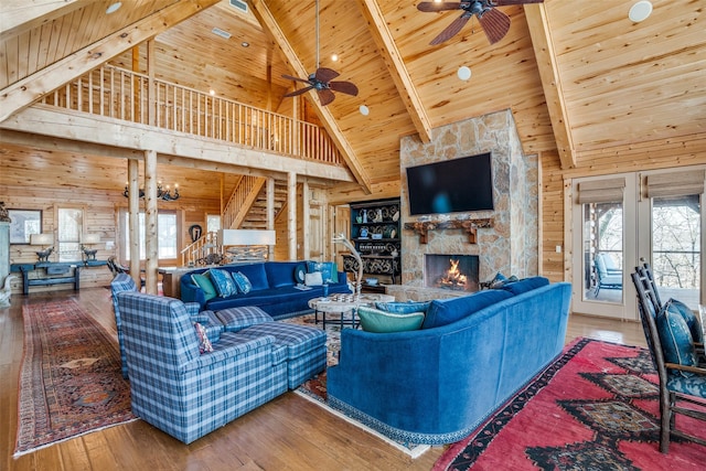 living room with wood ceiling, hardwood / wood-style flooring, a stone fireplace, and wood walls