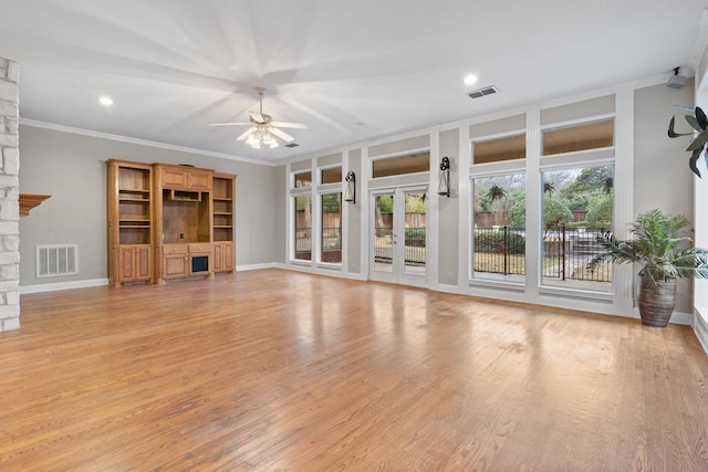 unfurnished living room featuring ceiling fan, light wood-type flooring, a wealth of natural light, and a fireplace