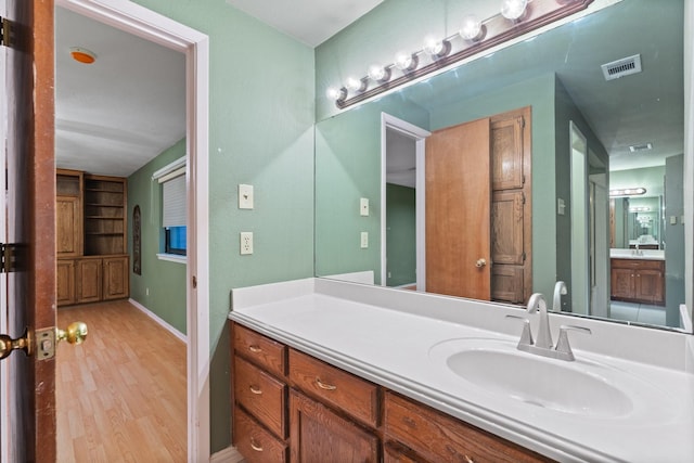 bathroom featuring vanity, hardwood / wood-style floors, and built in shelves