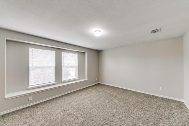 carpeted empty room with a textured ceiling