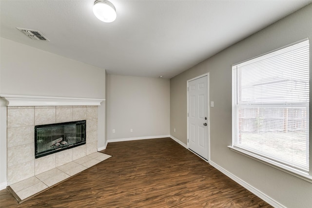 unfurnished living room with dark hardwood / wood-style floors and a tiled fireplace