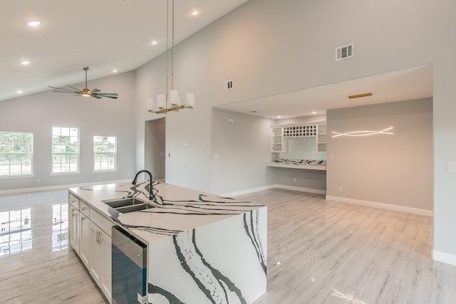 kitchen featuring white cabinetry, high vaulted ceiling, light hardwood / wood-style floors, ceiling fan with notable chandelier, and stainless steel dishwasher