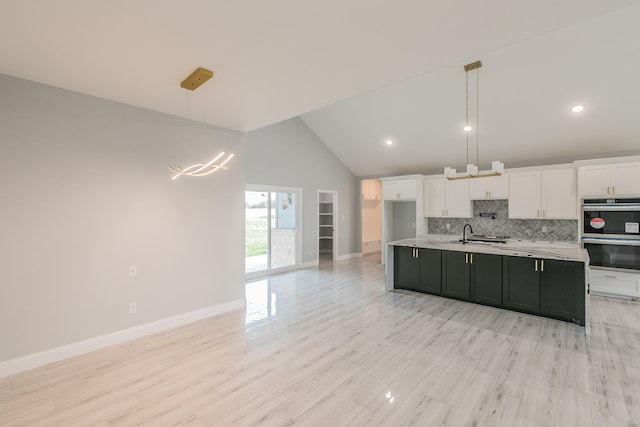 kitchen featuring pendant lighting, white cabinetry, decorative backsplash, stainless steel double oven, and light wood-type flooring