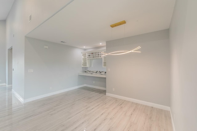 unfurnished room with an inviting chandelier and light hardwood / wood-style flooring