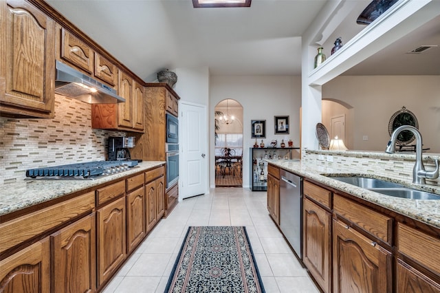 kitchen with light tile patterned flooring, sink, light stone counters, tasteful backsplash, and appliances with stainless steel finishes
