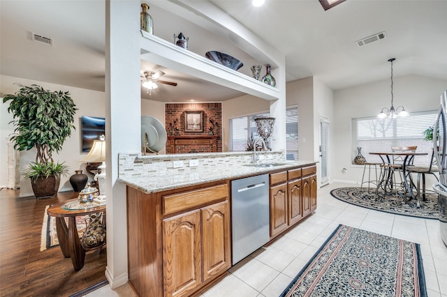 kitchen featuring a healthy amount of sunlight, dishwasher, sink, and light stone countertops