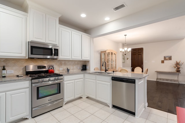 kitchen with appliances with stainless steel finishes, sink, white cabinetry, and kitchen peninsula