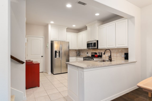 kitchen featuring white cabinetry, stainless steel appliances, light stone countertops, sink, and tasteful backsplash