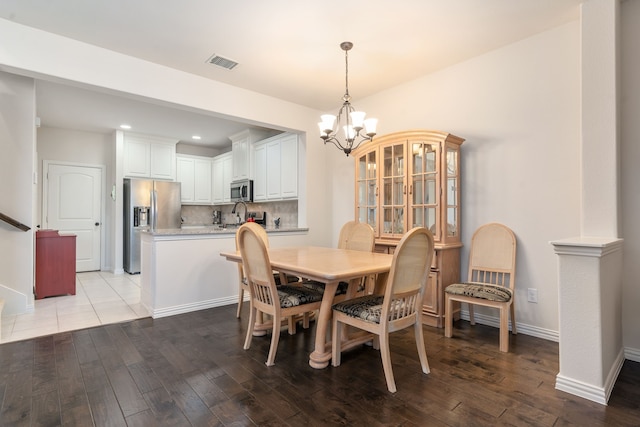 dining area with sink, light hardwood / wood-style floors, and a chandelier