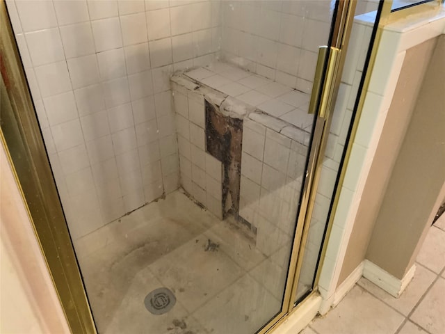 bathroom with tile patterned flooring and a tile shower